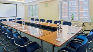 A conference room with a long table, blue chairs, and a projector screen.