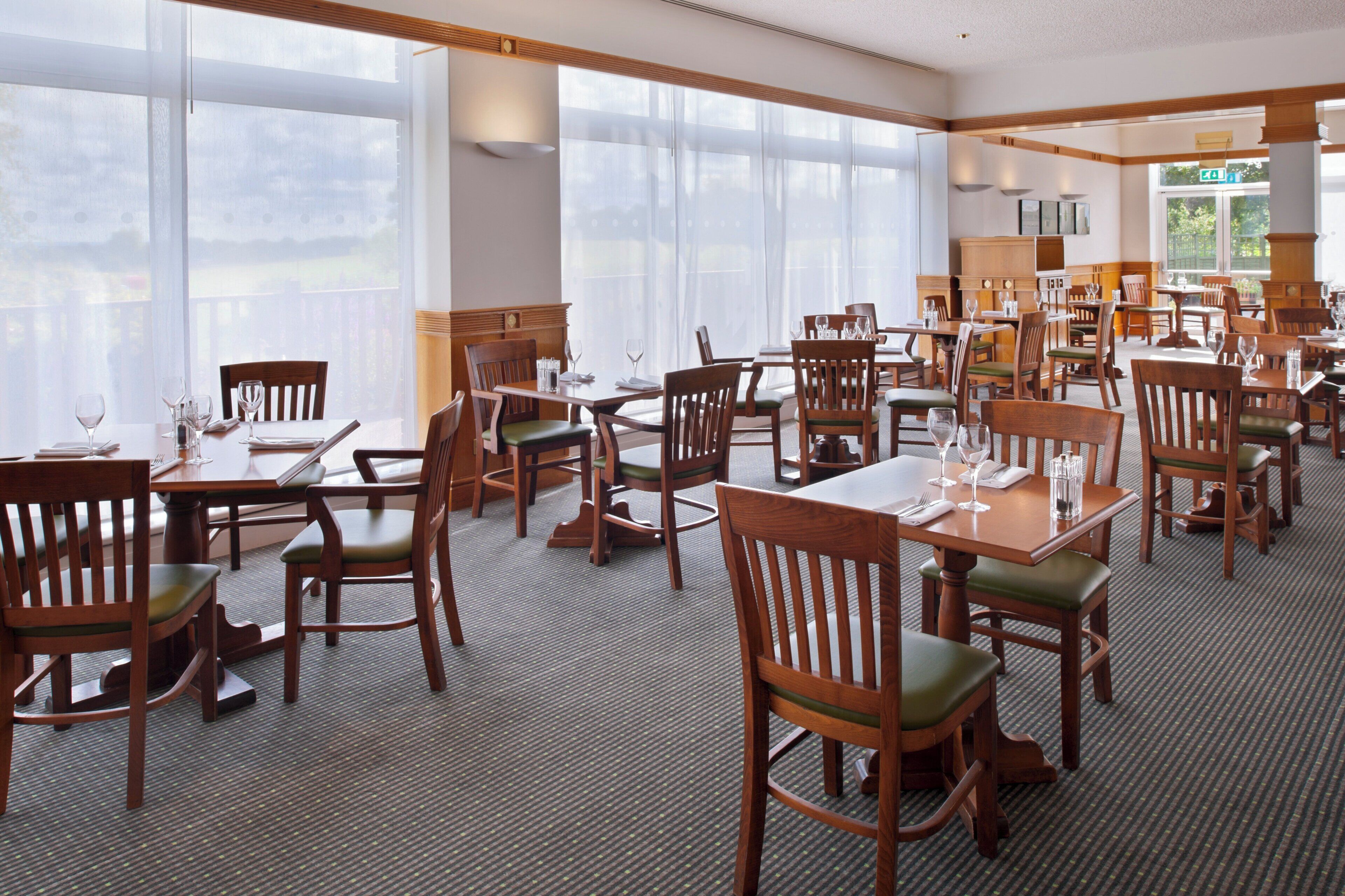 A restaurant with multiple tables and chairs, large windows, and a view of the outdoors.
