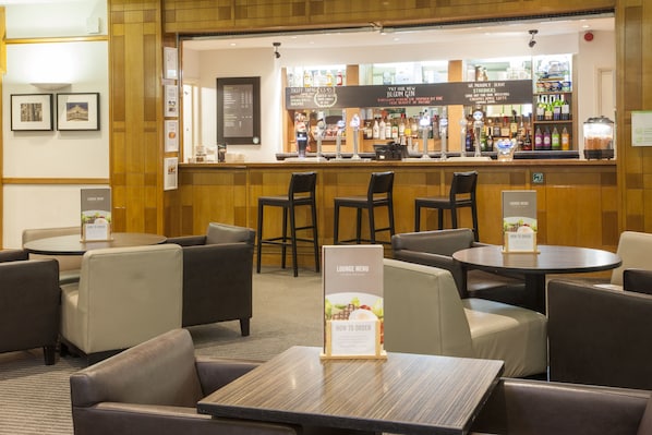 Un espace bar avec un comptoir, des tabourets de bar et un panneau indiquant le menu du salon.
