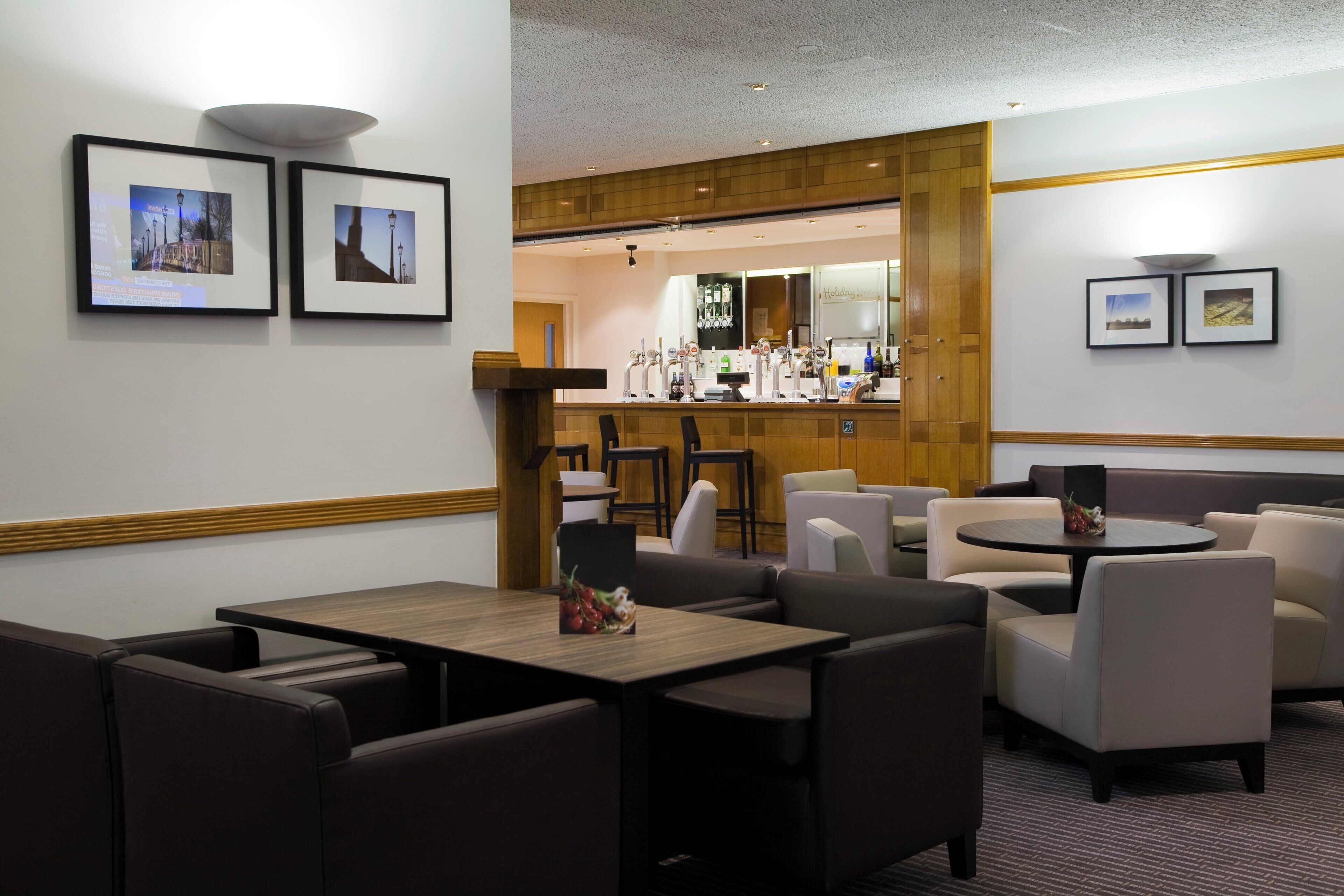 A hotel lobby with seating areas, a bar, and framed pictures on the walls.