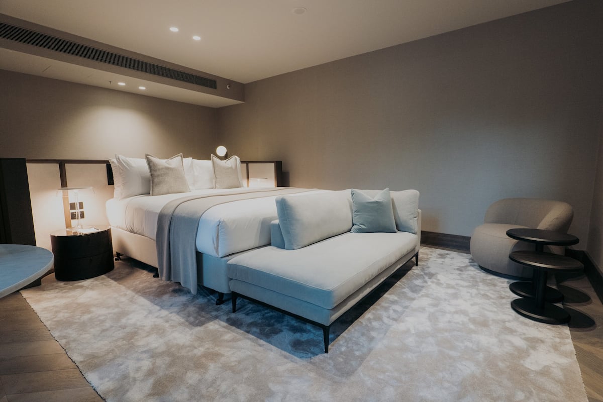 A modern bedroom with a bed, a sofa, a chair, and a small table.