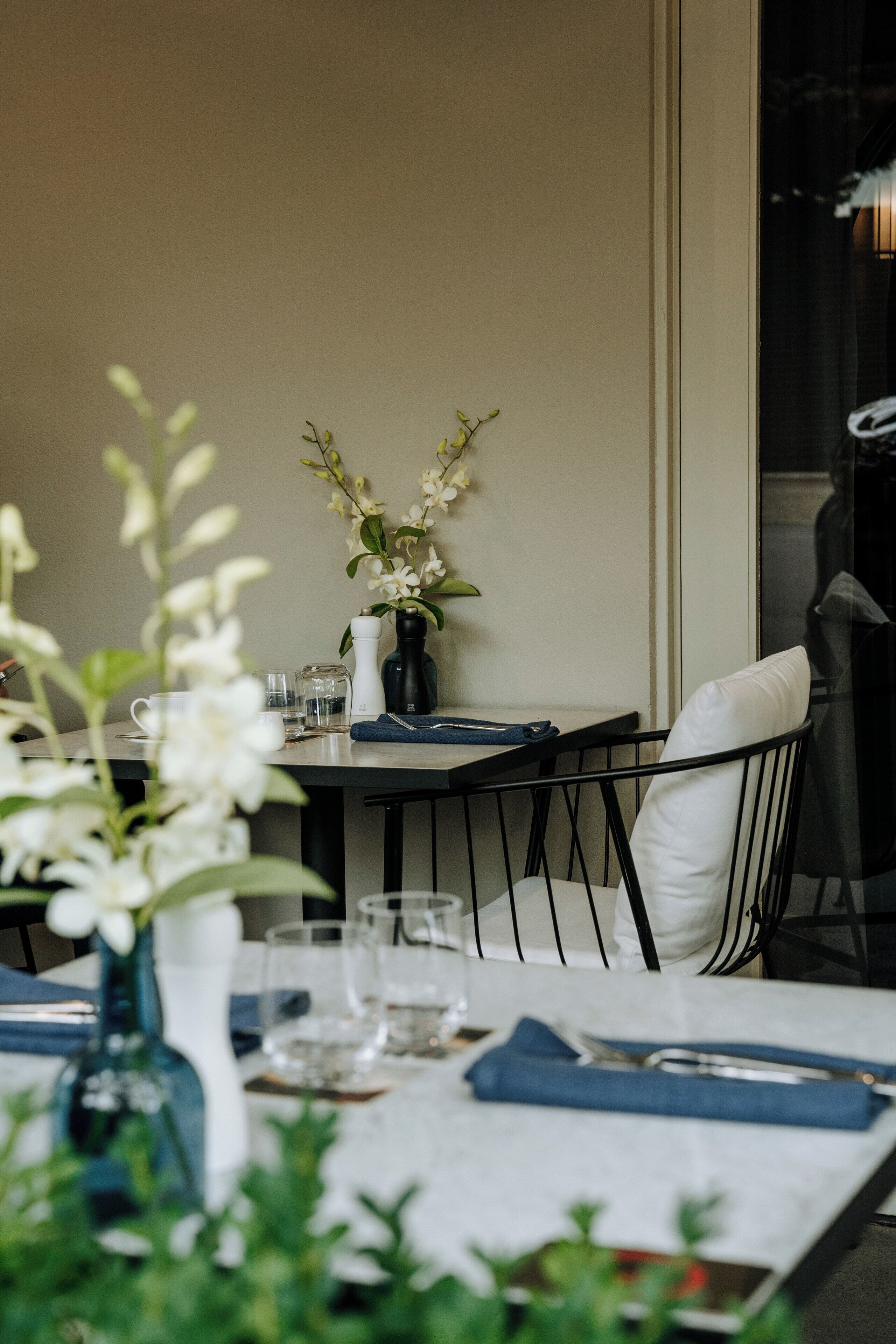 A dining table set with a vase of flowers, glasses, and cutlery.