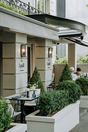 An outdoor seating area with tables and chairs, a name sign, and a railing.