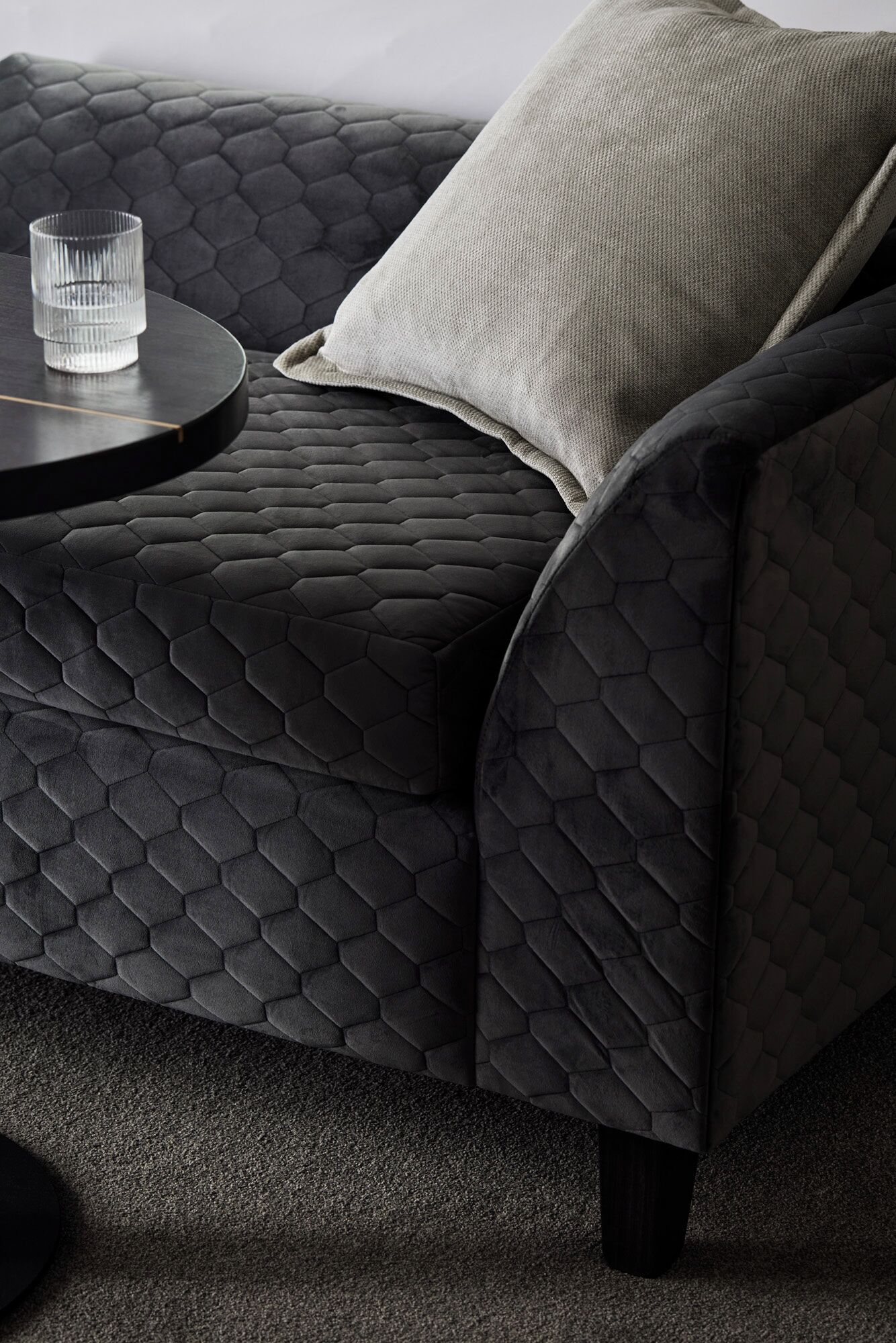 A modern sofa with a geometric pattern upholstery and a round side table.