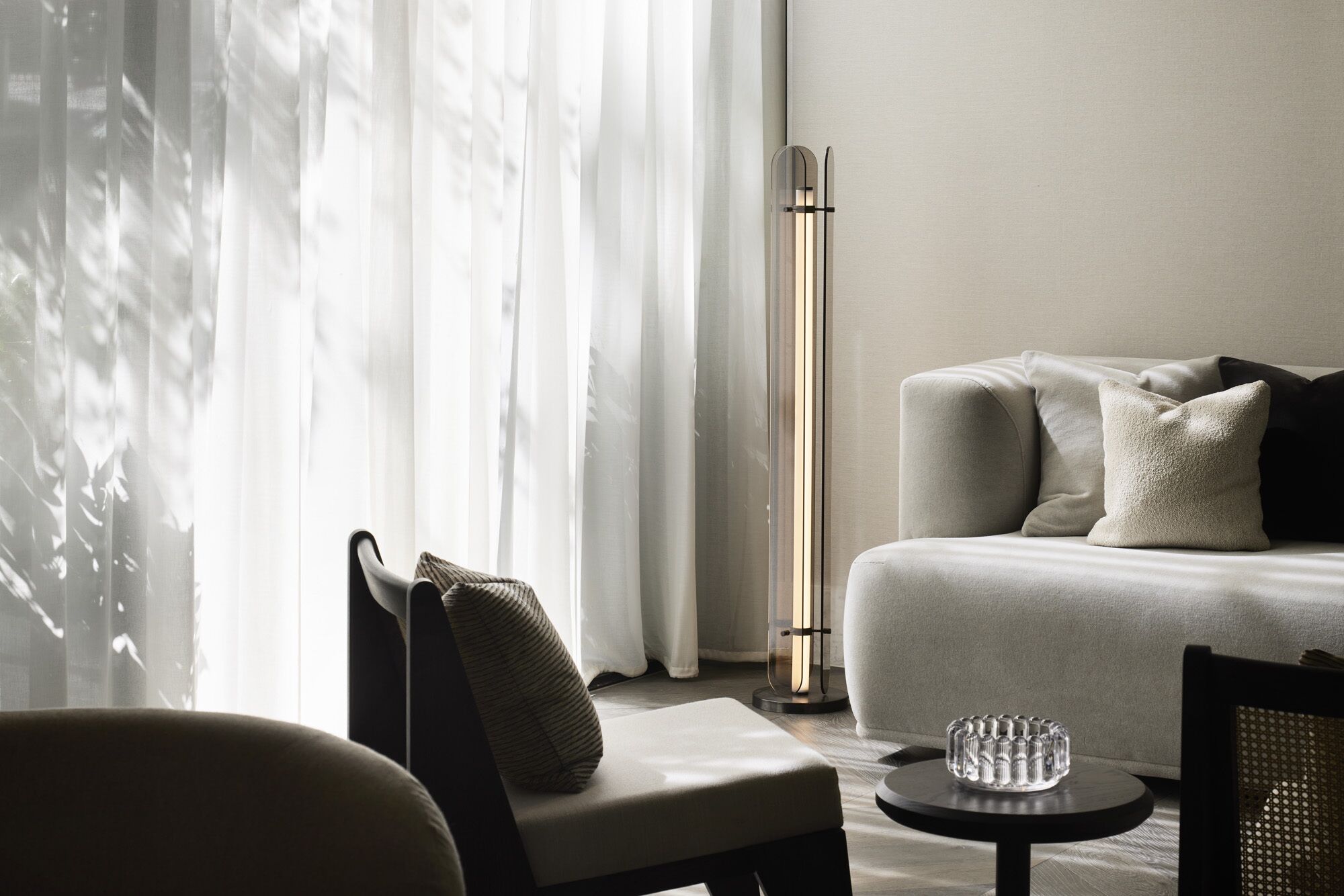 Ein modernes Wohnzimmer mit einer Couch, einem Sessel, einem kleinen Tisch und einer Stehlampe.