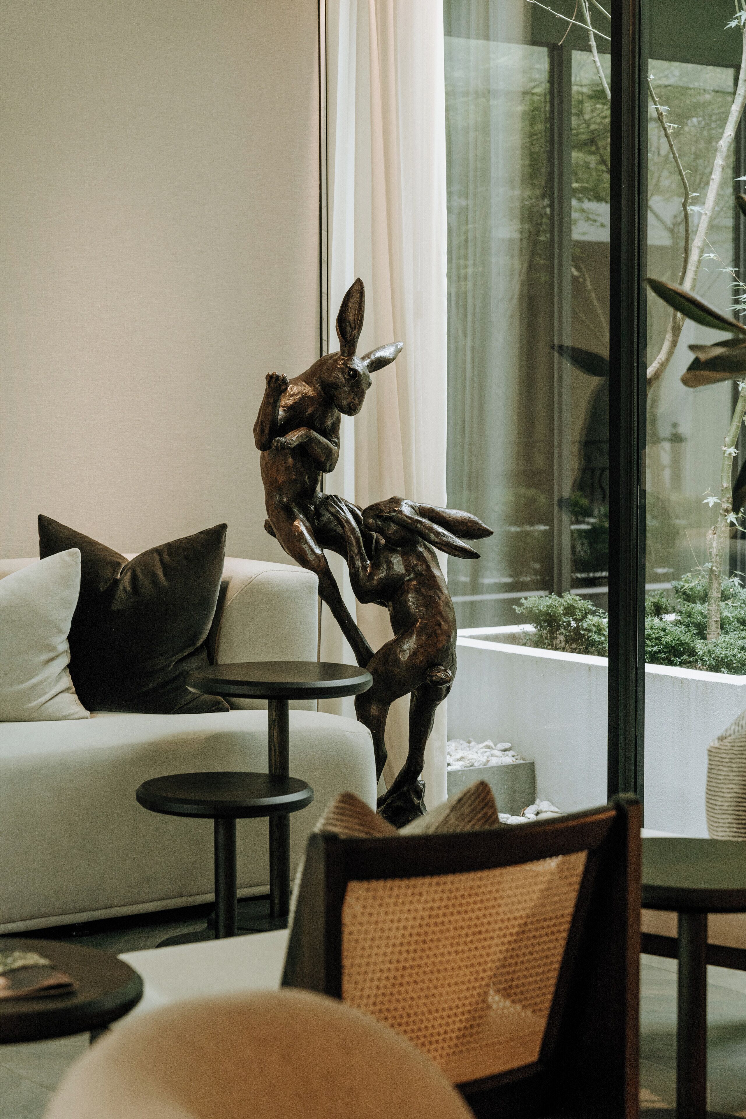 A modern living room with a sofa, a small round table, and a decorative bronze sculpture of a rabbit.