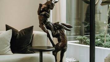 A modern living room with a sofa, a small round table, and a decorative bronze sculpture of a rabbit.