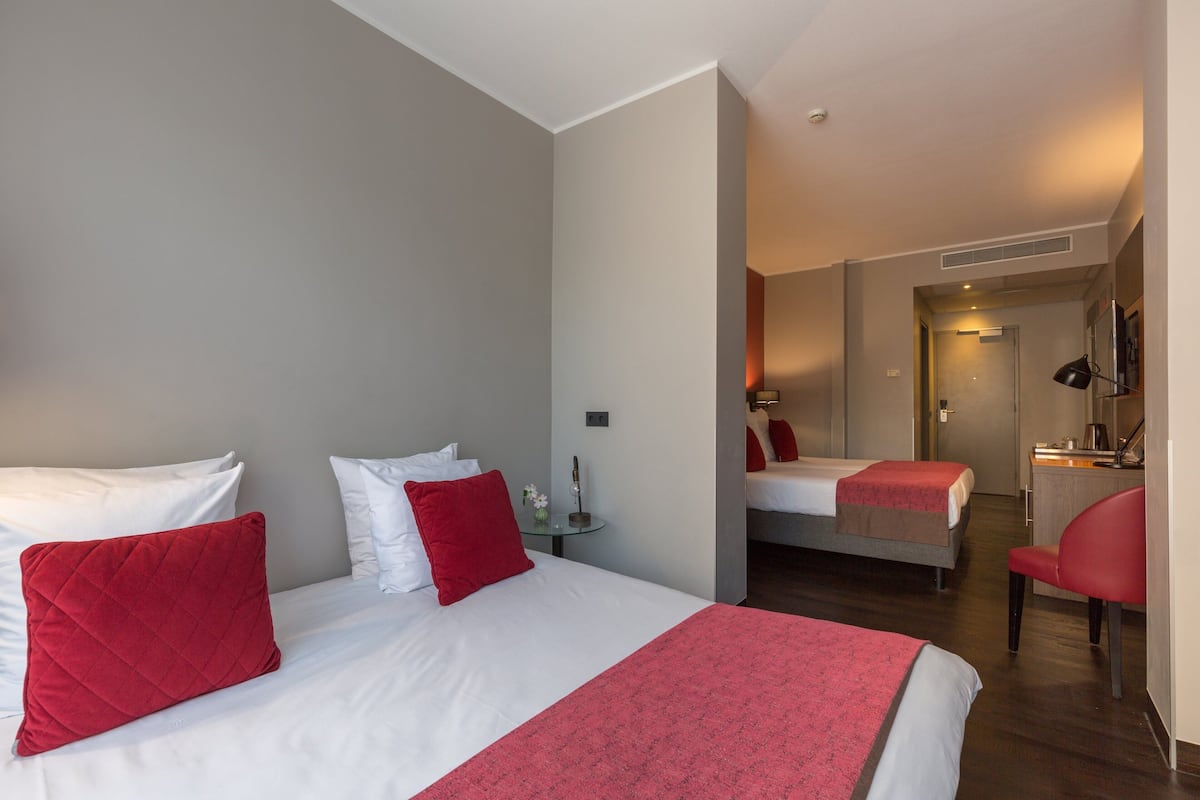 A hotel room with a large bed, a smaller bed, a desk, and a chair.
