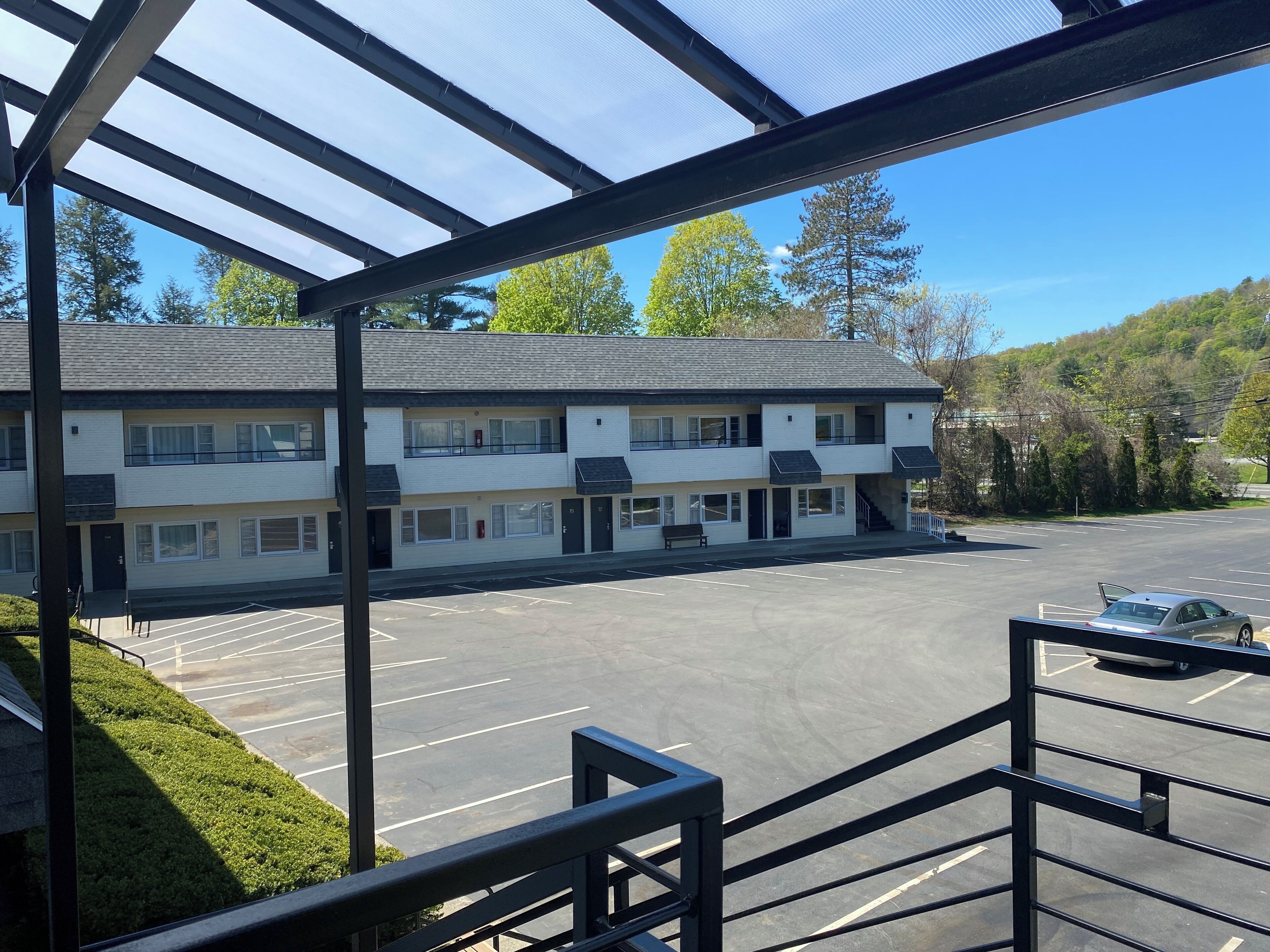 A multi-story motel with a parking lot and a covered walkway.