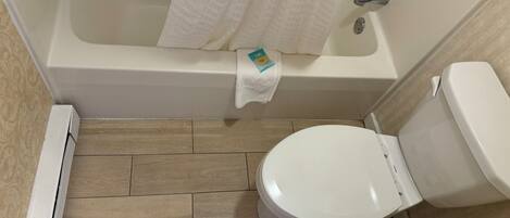 A bathroom with a bathtub, toilet, and a shower curtain.