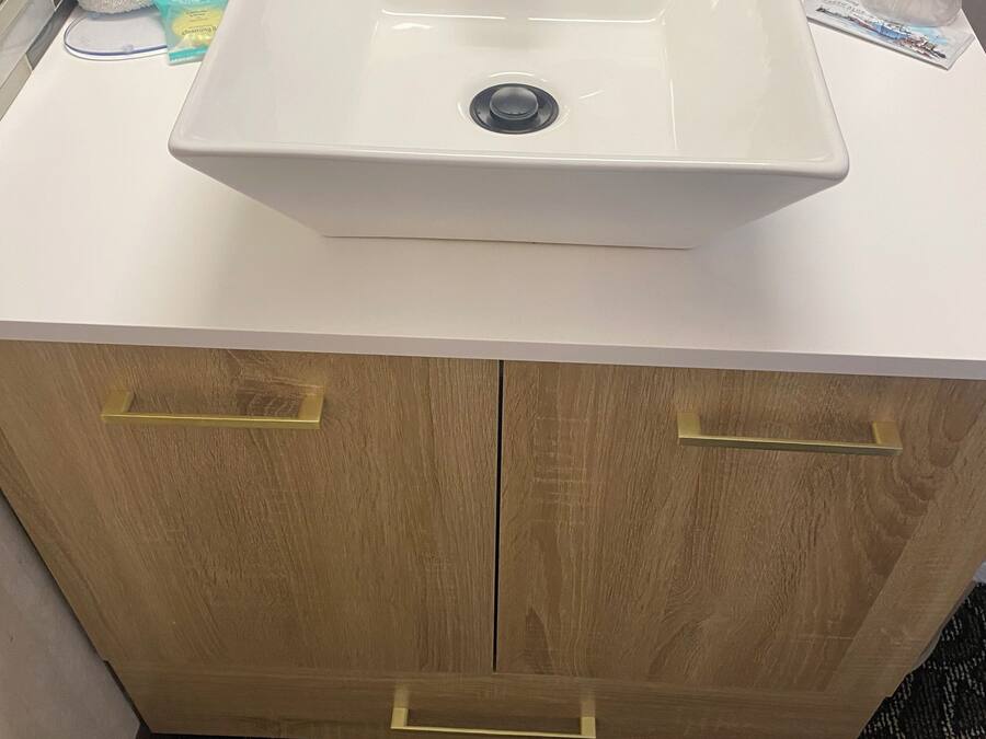 A bathroom with a white sink, wooden cabinets, and a patterned carpet.