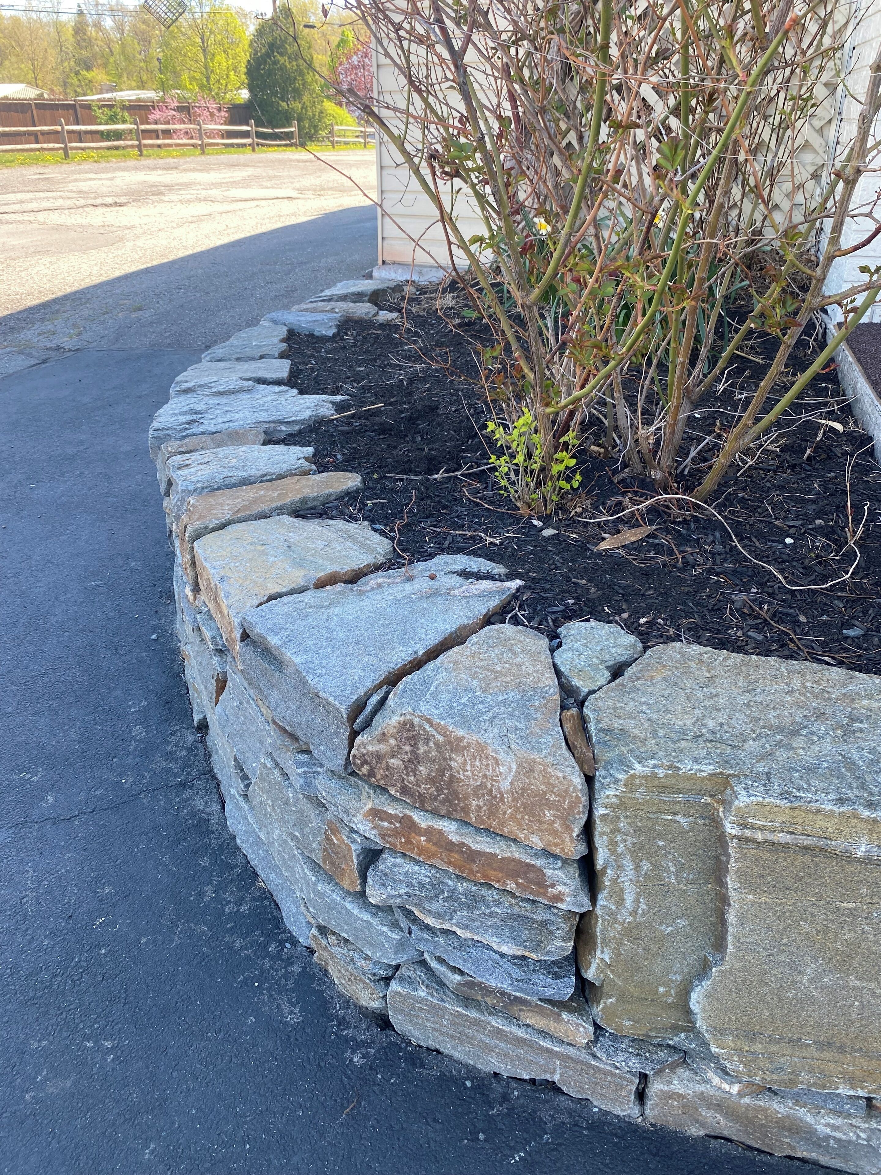 A stone planter with a small tree and shrubs.
