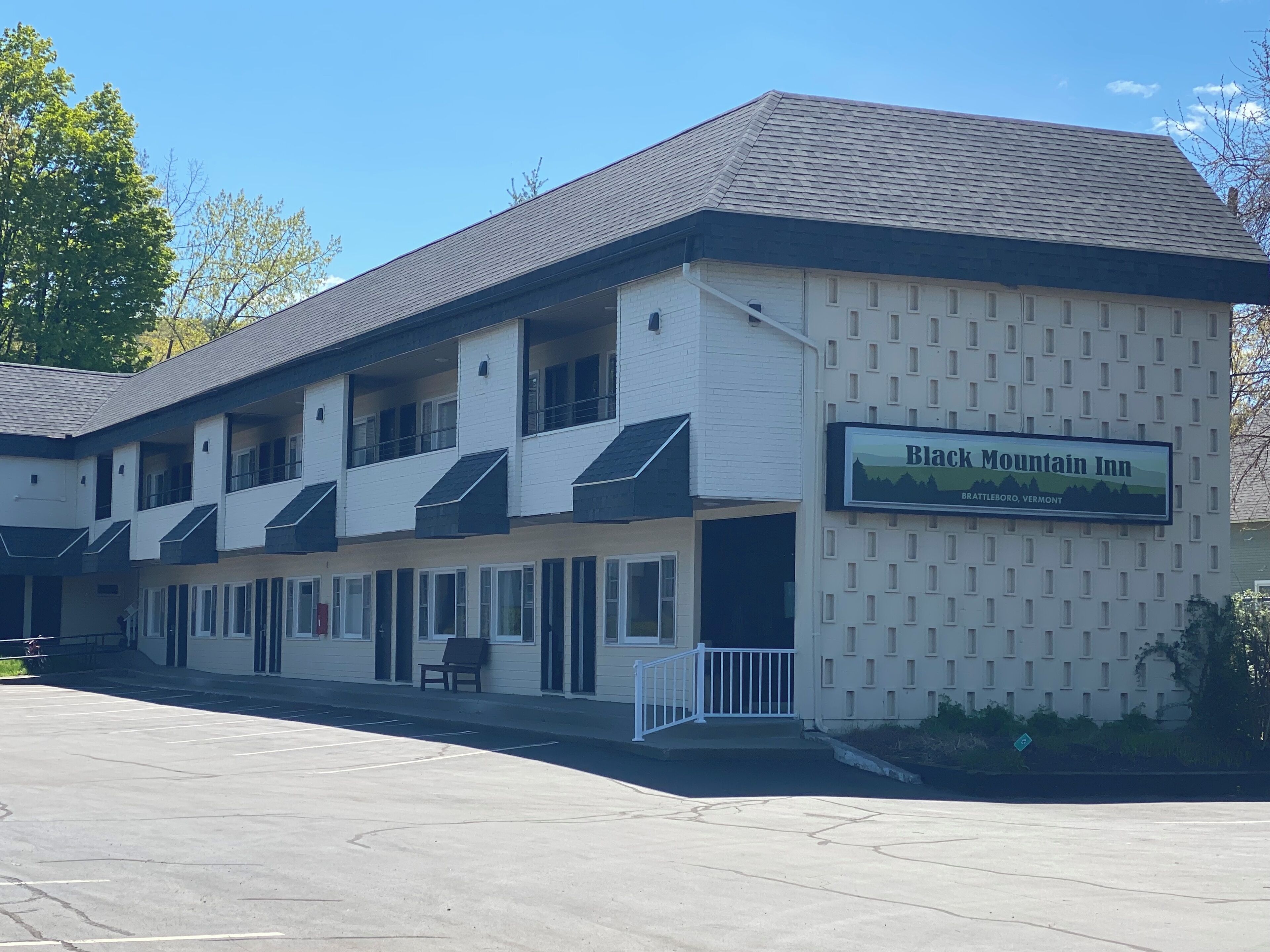 A building with a sign reading "Black Mountain Inn" in Brattleboro, Vermont. It features a multi-story structure with a flat roof and a parking lot in front.