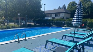 A swimming pool with lounge chairs and a covered umbrella. - Black Mountain Inn (Brattleboro)
