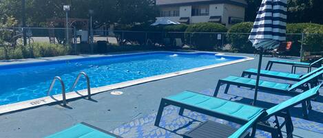 A swimming pool with lounge chairs and a covered umbrella.