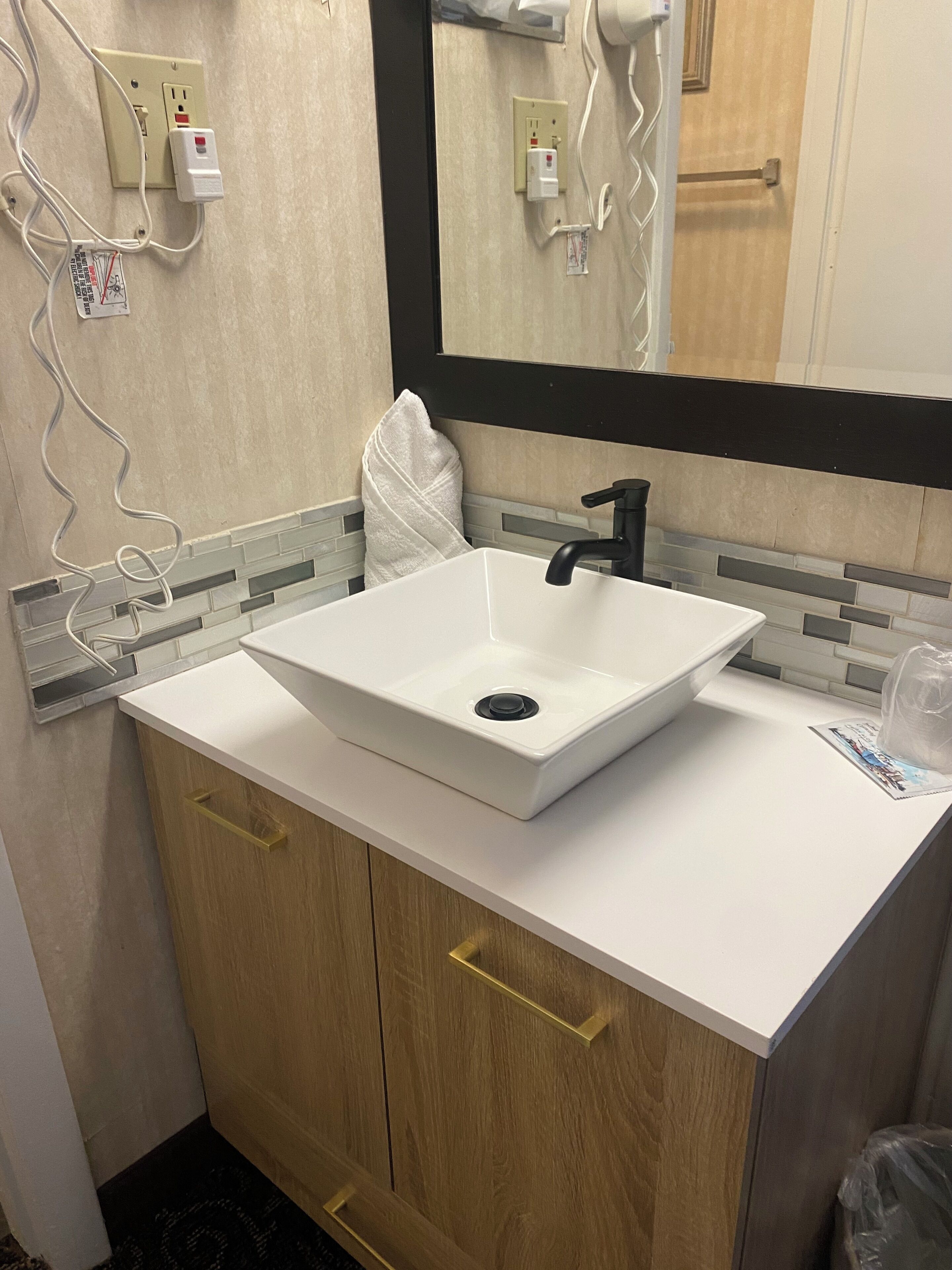 A bathroom with a white sink, wooden cabinets, and a mirror.
