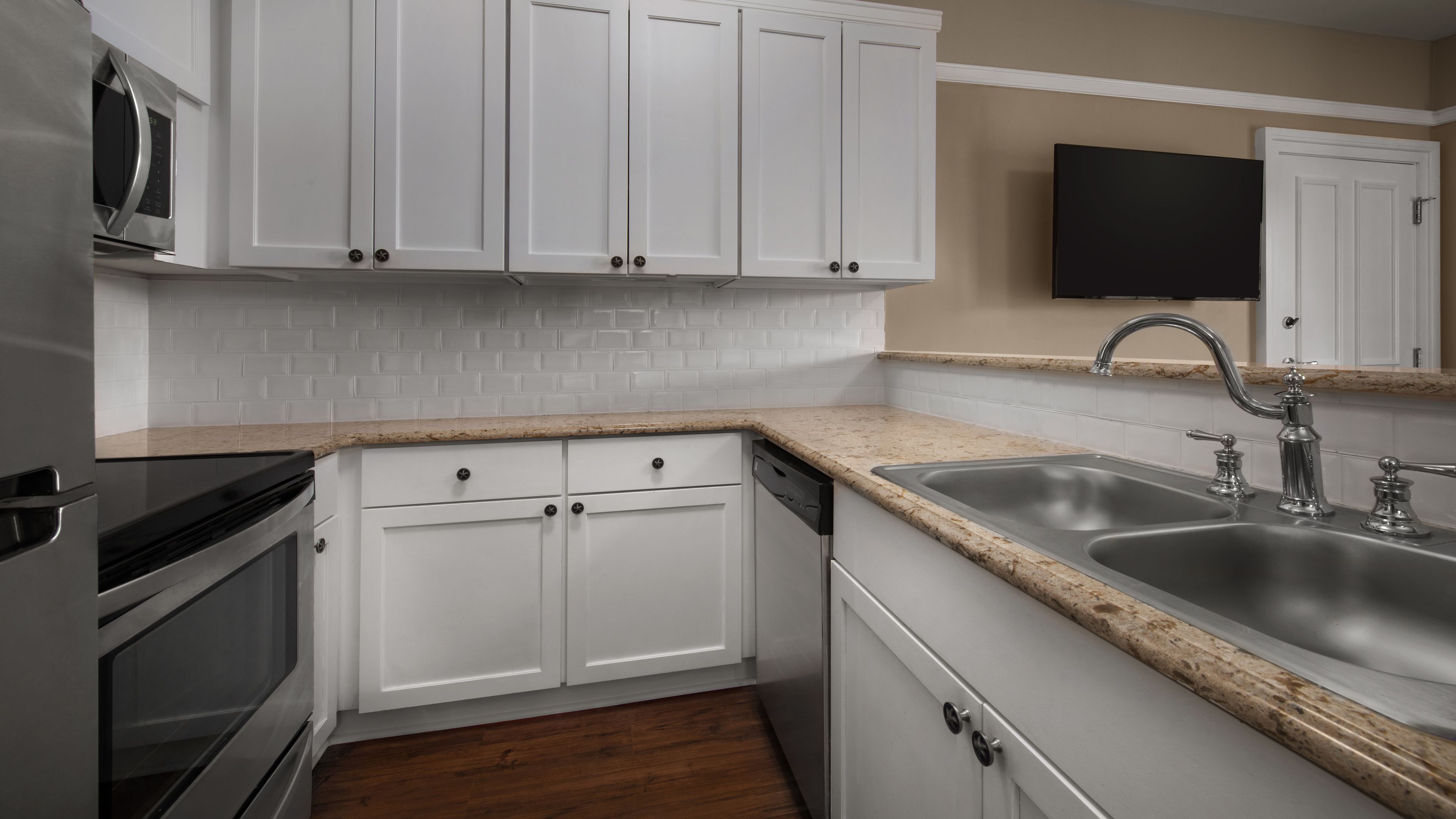 A kitchen with white cabinets, a stainless steel sink, and a microwave.