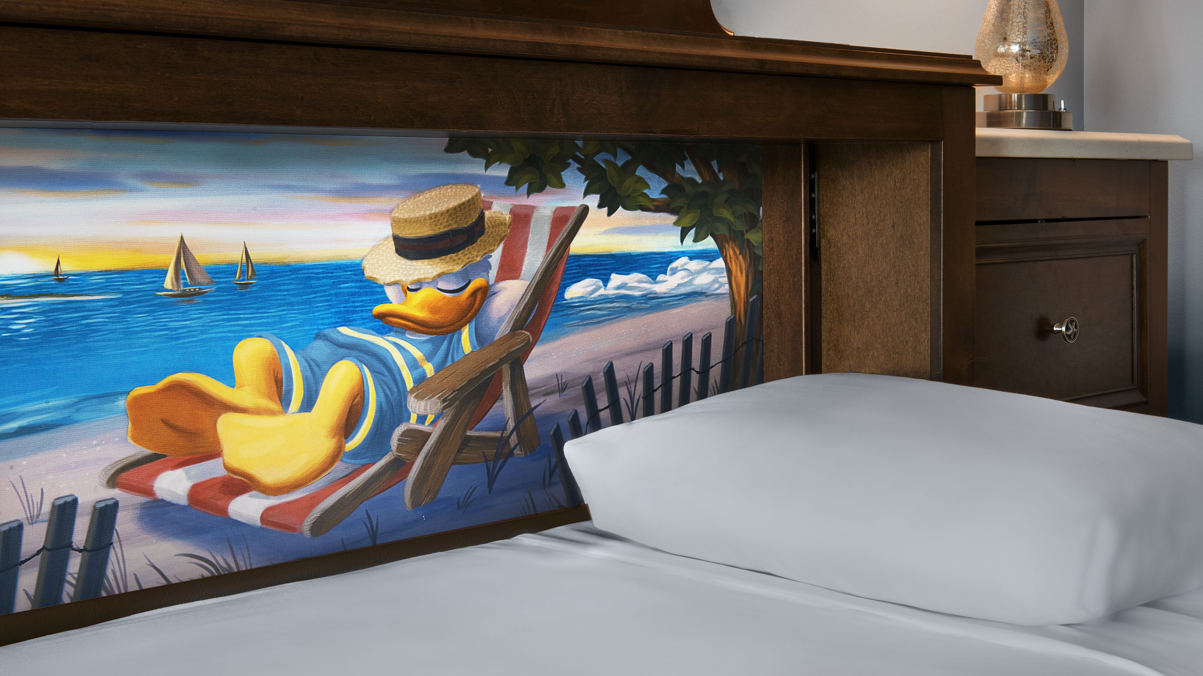 Un lit orné d’une fresque représentant un canard de dessin animé se relaxant au bord de la mer.