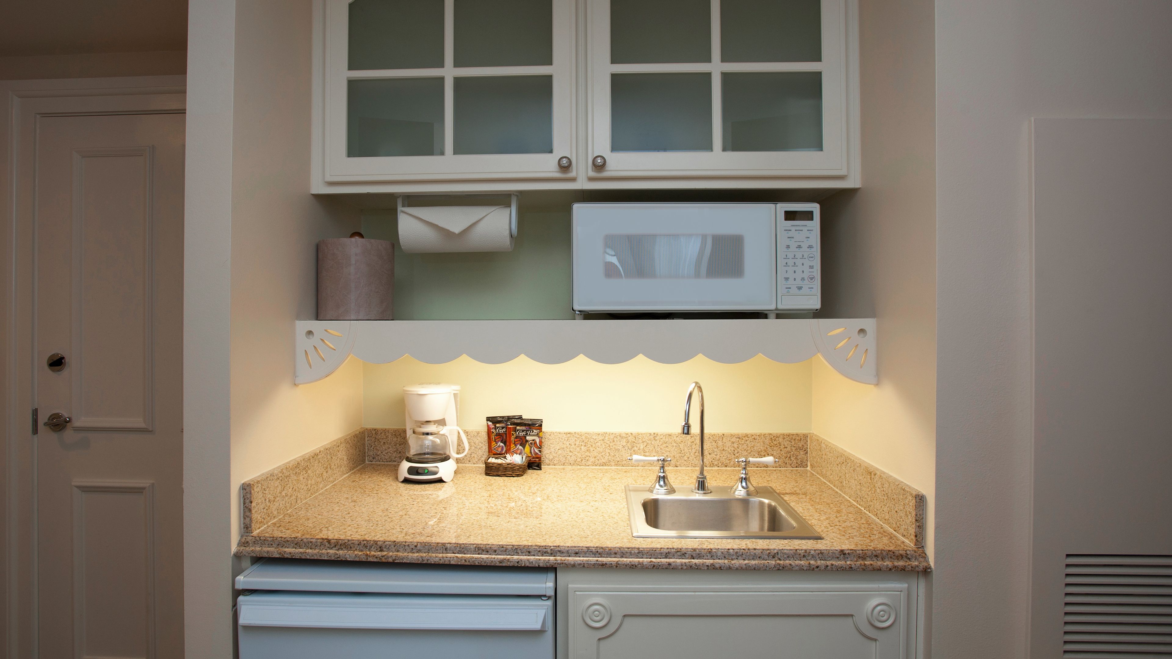 A kitchen with a microwave, coffee maker, and sink.