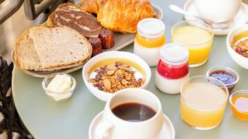 A table with breakfast items including bread, pastries, and beverages.
