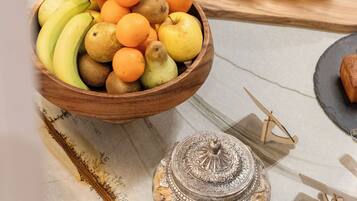 A wooden bowl filled with fruits and a loaf of bread on a table.