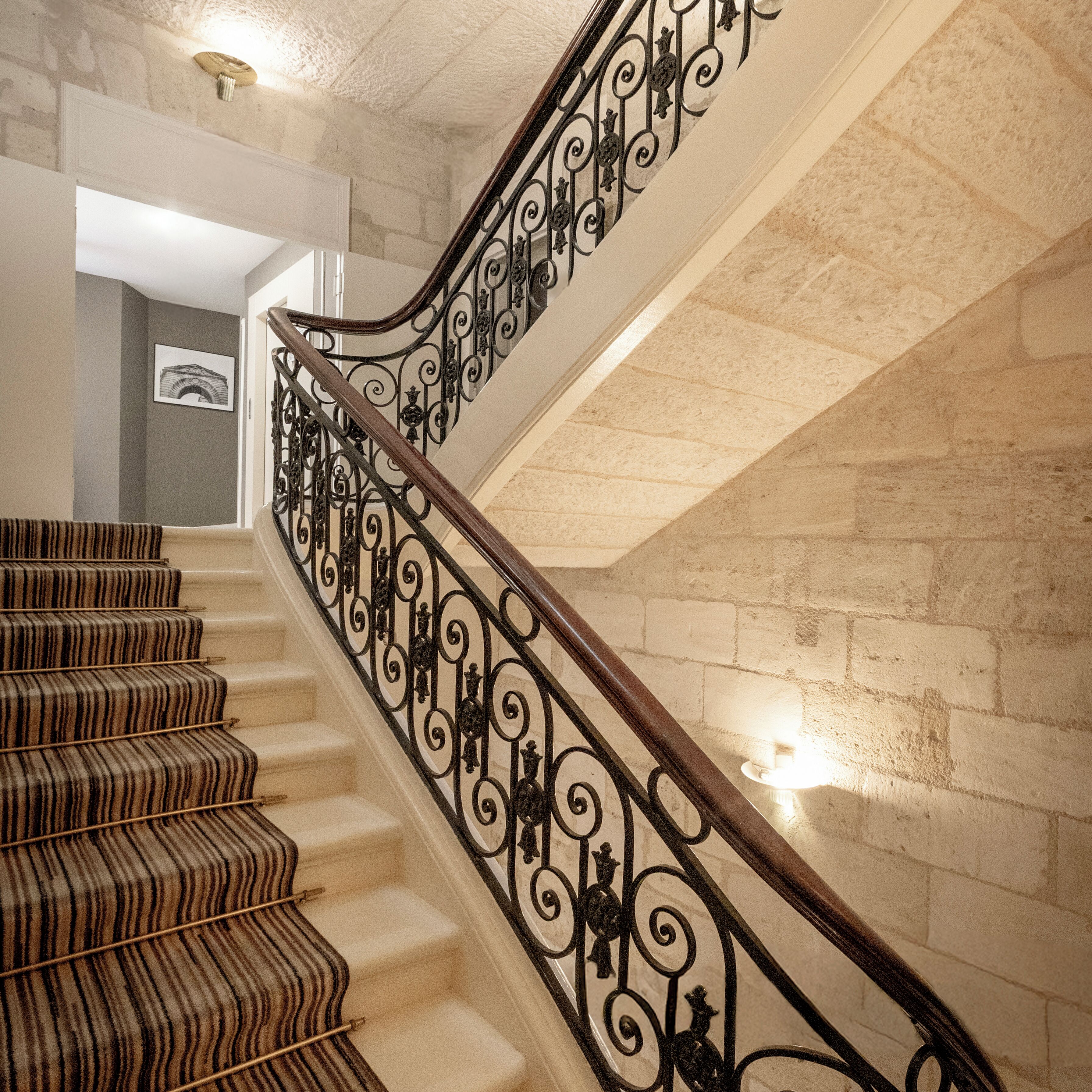 A staircase with ornate black metal railings and a patterned carpet.