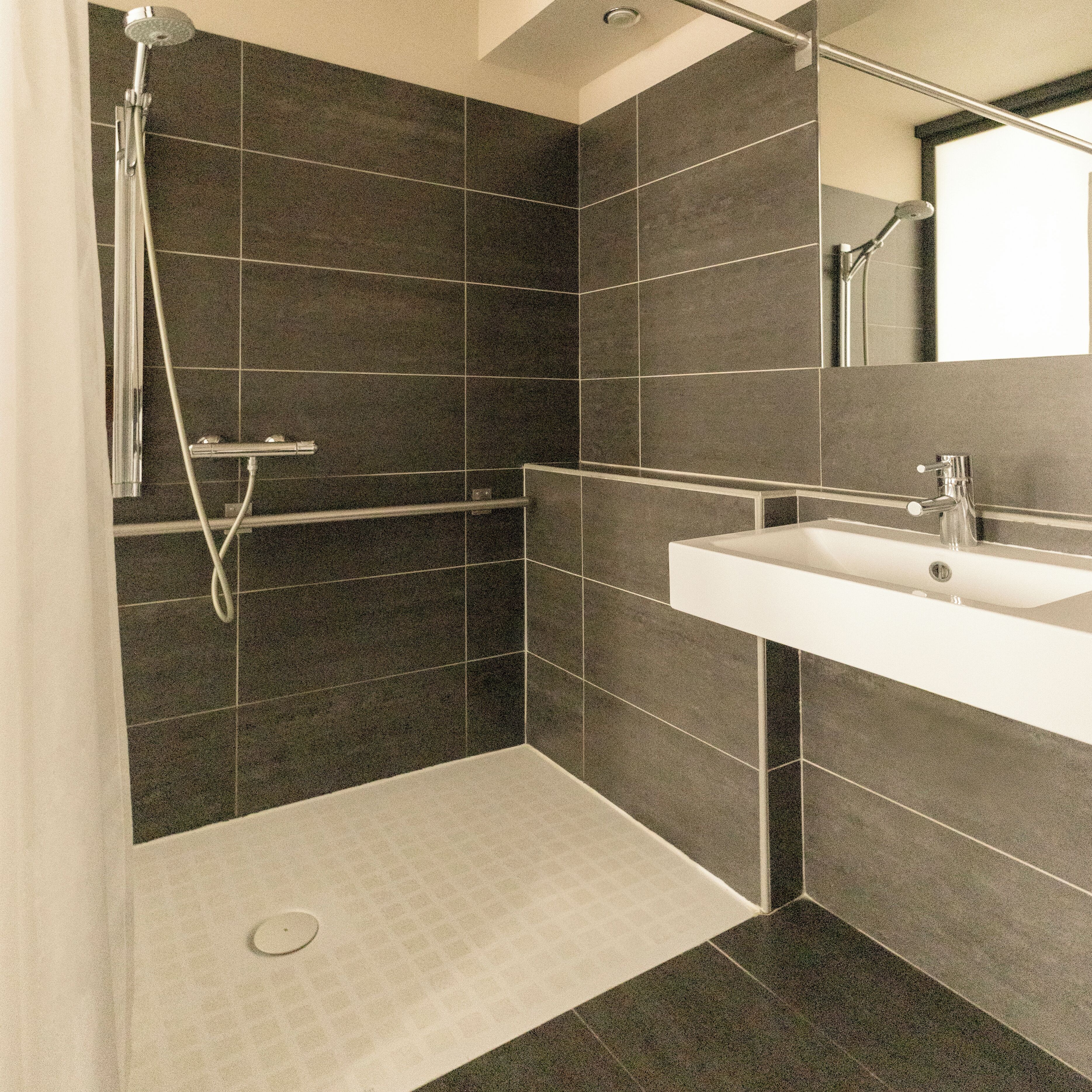 Une salle de bain moderne avec une douche, un lavabo et un miroir.