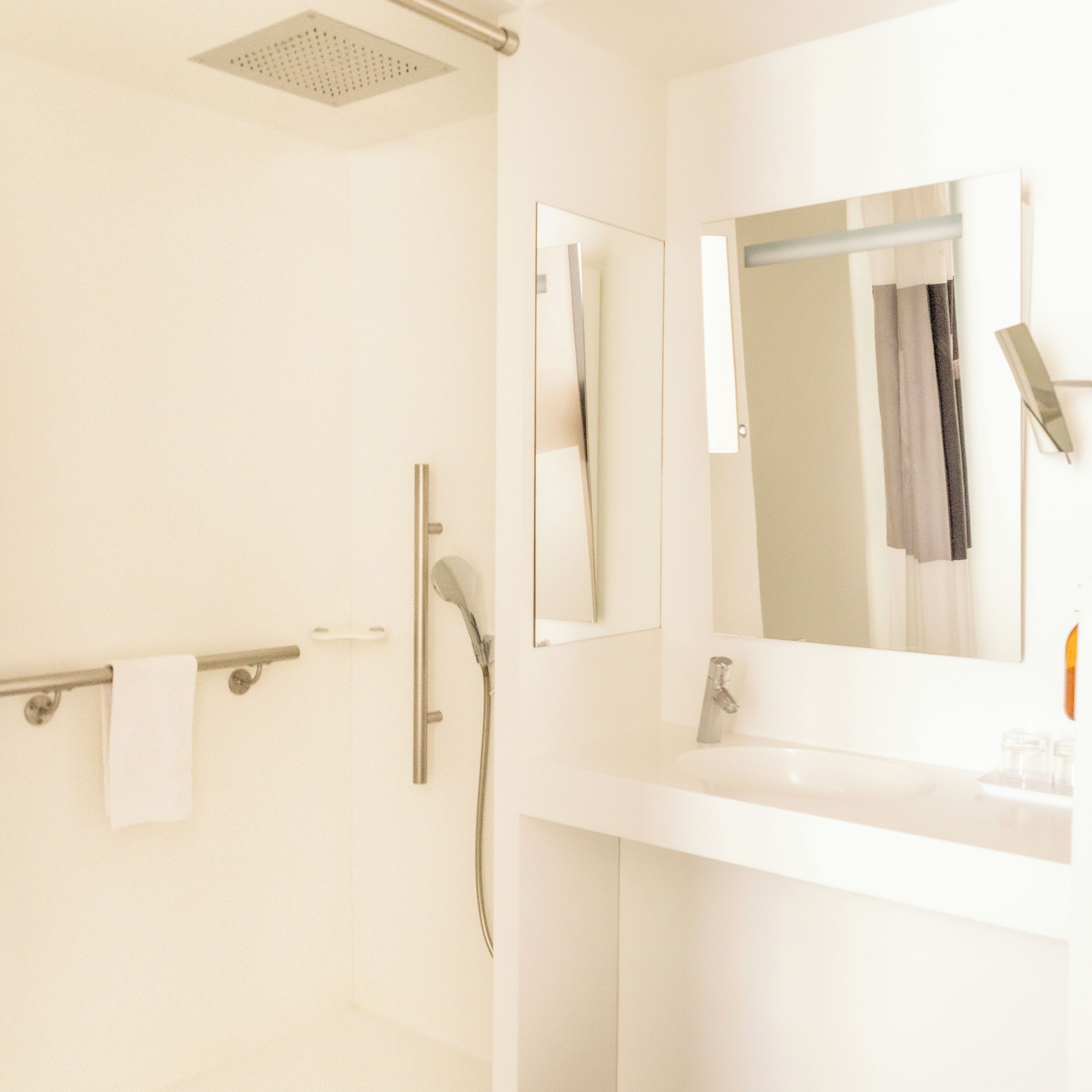 Une salle de bain moderne avec une douche, un lavabo et un miroir.