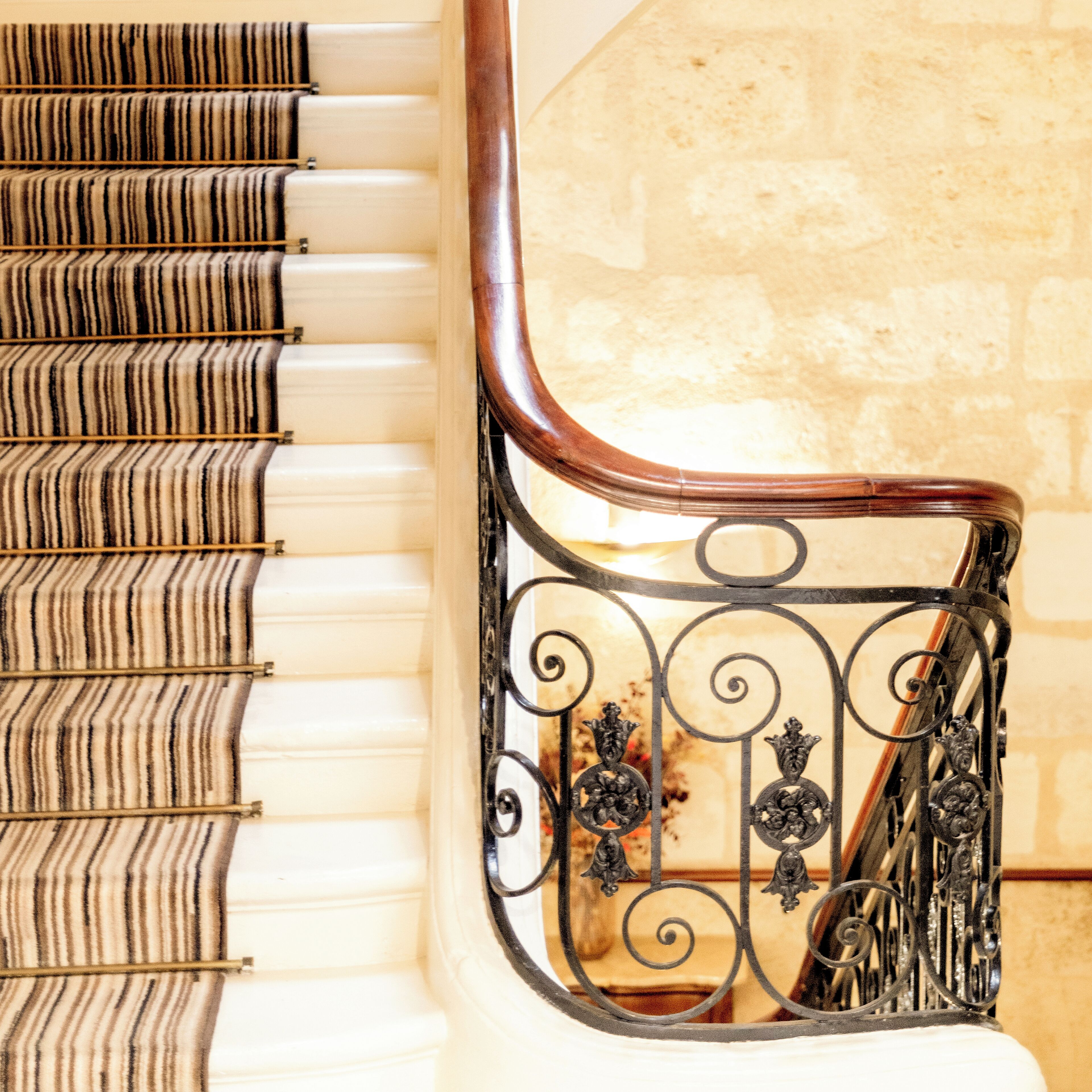 Un escalier doté d’une main courante en bois et d’une rampe métallique ornée d’éléments décoratifs.