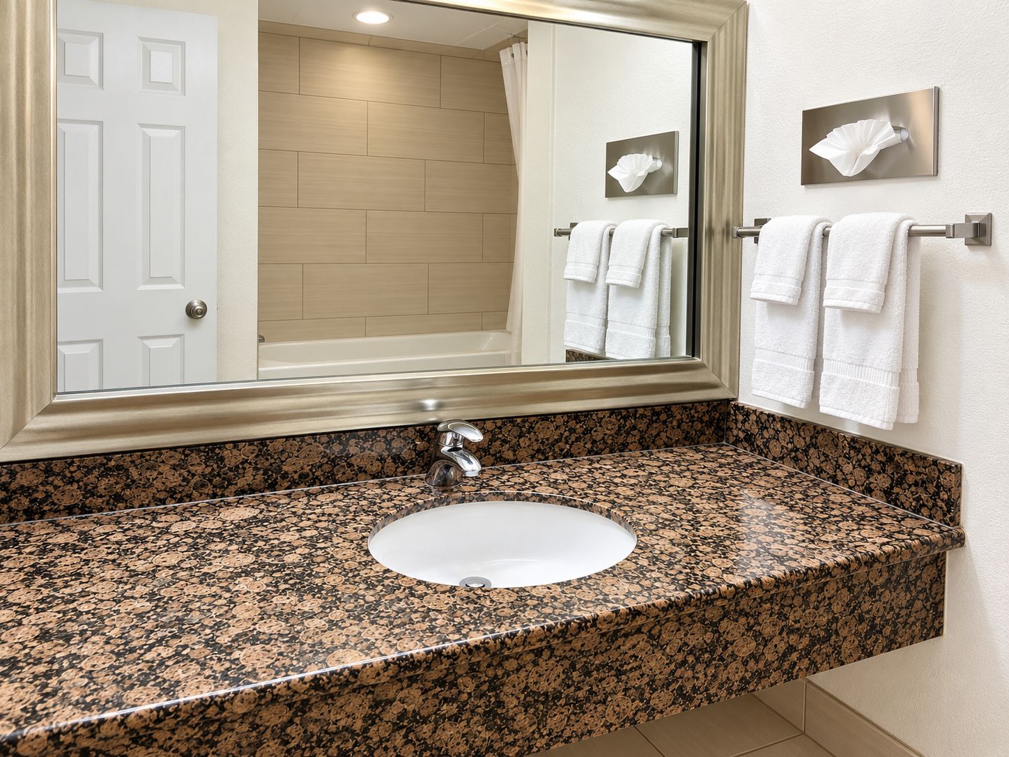 A bathroom with a granite countertop sink, a mirror, a towel rack, and a door.