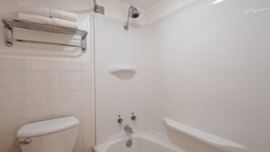 A bathroom with a toilet, a bathtub, and a shower. There is a towel rack with towels on it. - Sturgis Lodge & Suites, Travelodge by Wyndham (Sturgis)
