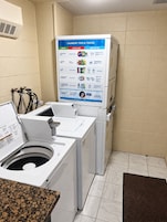 Zona de lavandería con un panel de consejos para el lavado, una lavadora de carga frontal y una secadora.