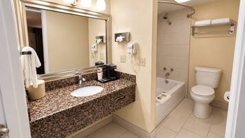 A bathroom with a sink, mirror, towel rack, and a shower area.