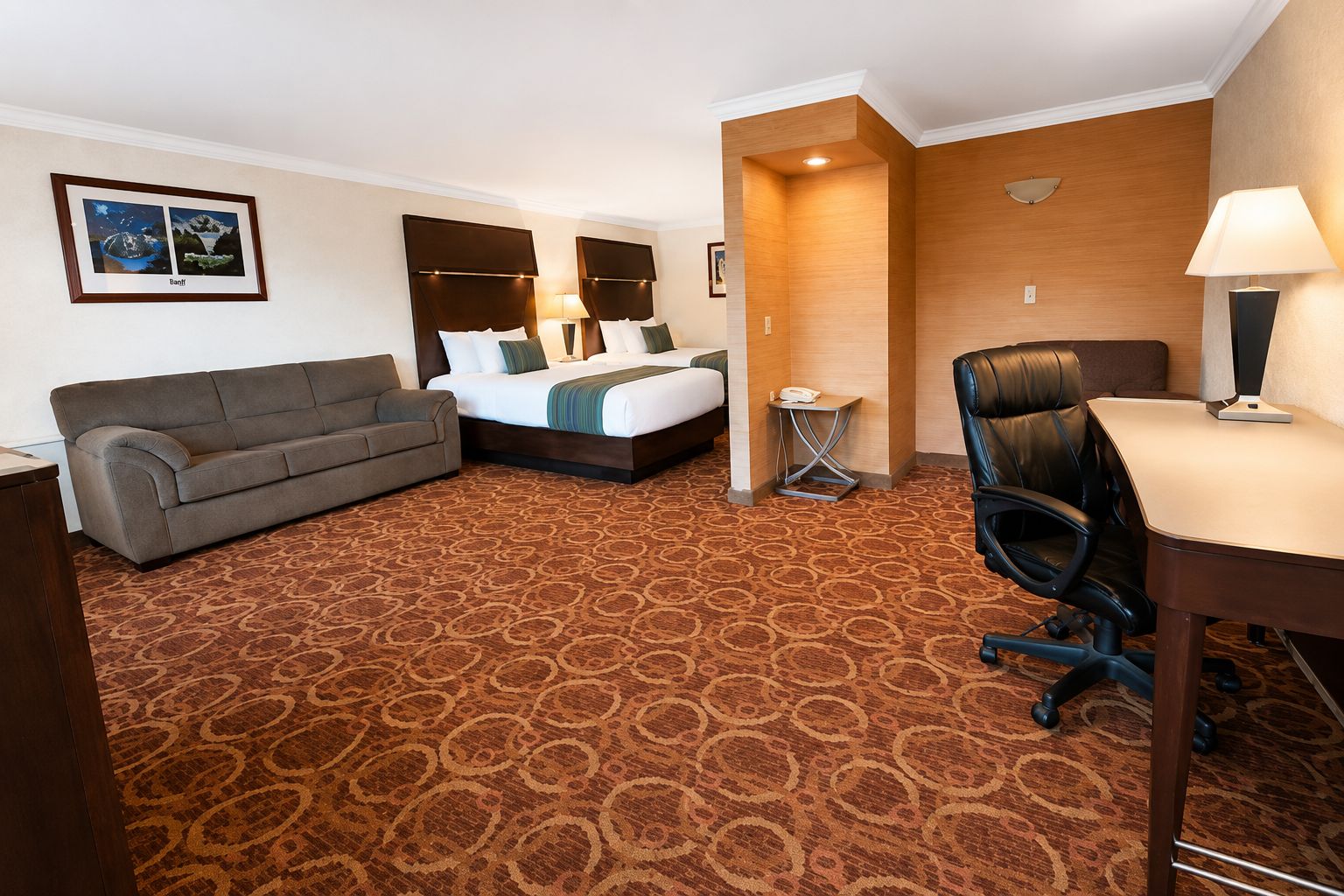 Quarto de hotel com cama, sofá, escrivaninha e cadeira.