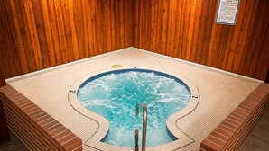 A hot tub with a wooden wall backdrop and a sign indicating spa rules.