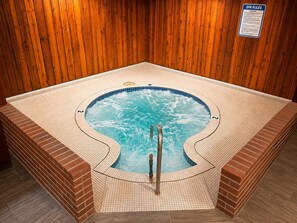 A hot tub with a wooden wall backdrop and a sign indicating spa rules. - Sturgis Lodge & Suites, Travelodge by Wyndham (Sturgis)