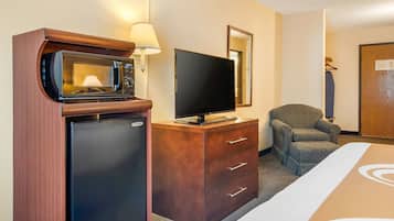 Habitación de hotel con minibar, televisor de pantalla plana, una silla y una cama.