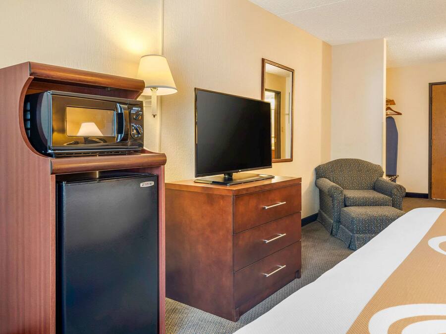 Habitación de hotel con minibar, televisor de pantalla plana, una silla y una cama.