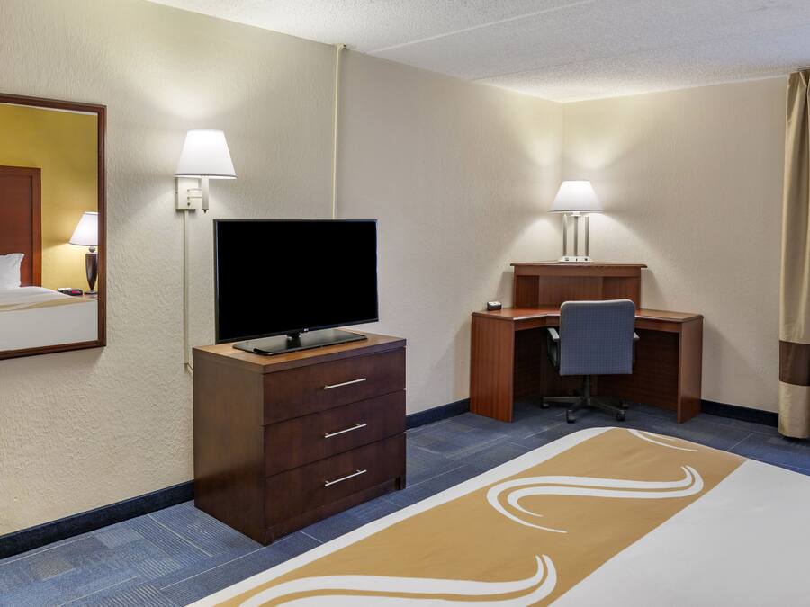 Una habitación de hotel con una cama, un escritorio, un televisor y una lámpara de escritorio.