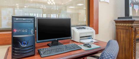 A wooden desk with a desktop computer, a keyboard, a mouse, and a printer.