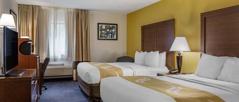 A hotel room with two beds, a desk with a TV, a lamp, and a painting on the wall.