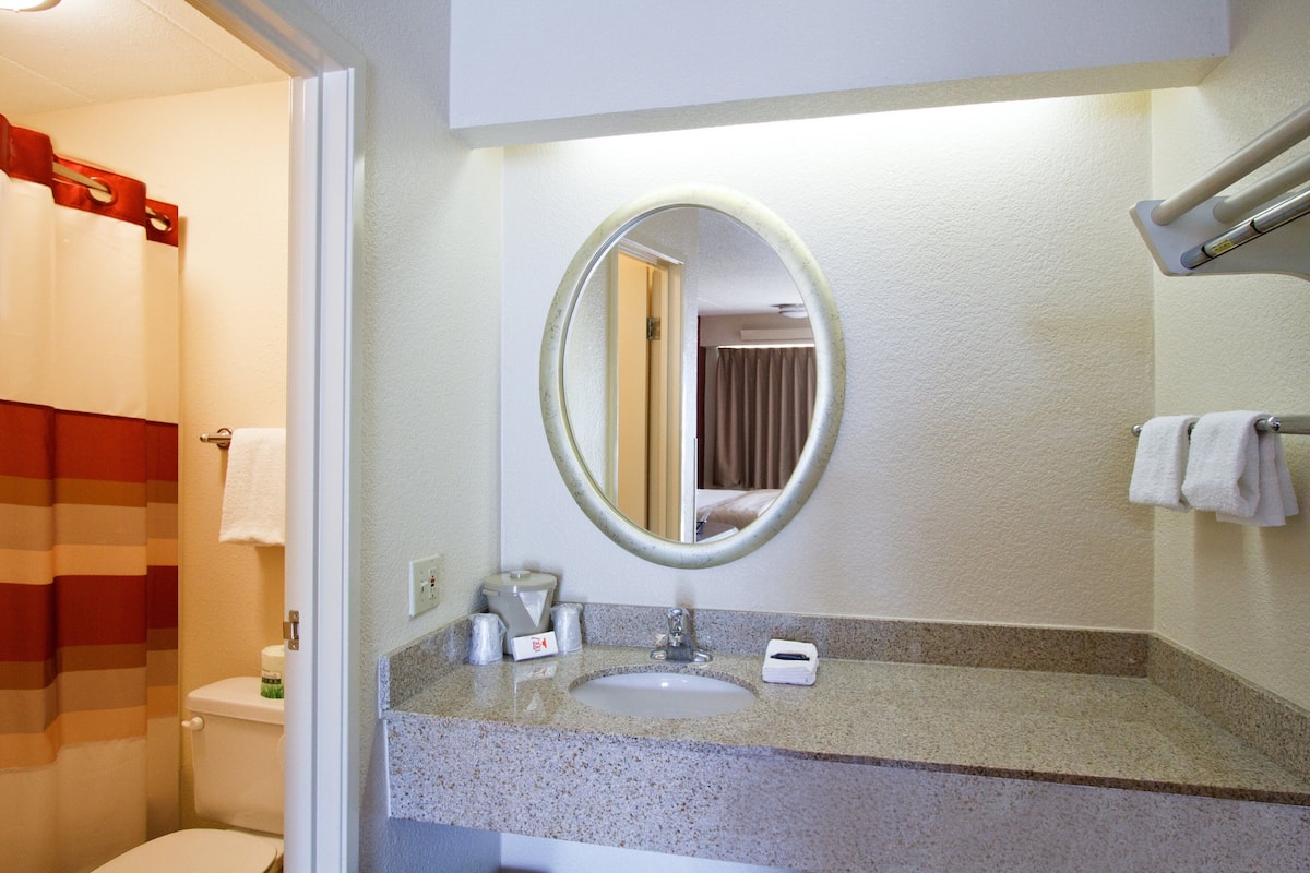 A bathroom with a sink, mirror, towel rack, and toilet.