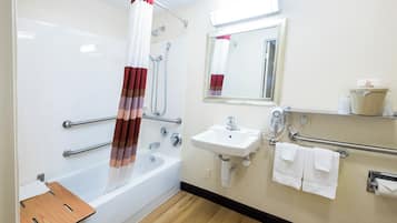 A bathroom with a bathtub, shower, sink, and hand dryer.