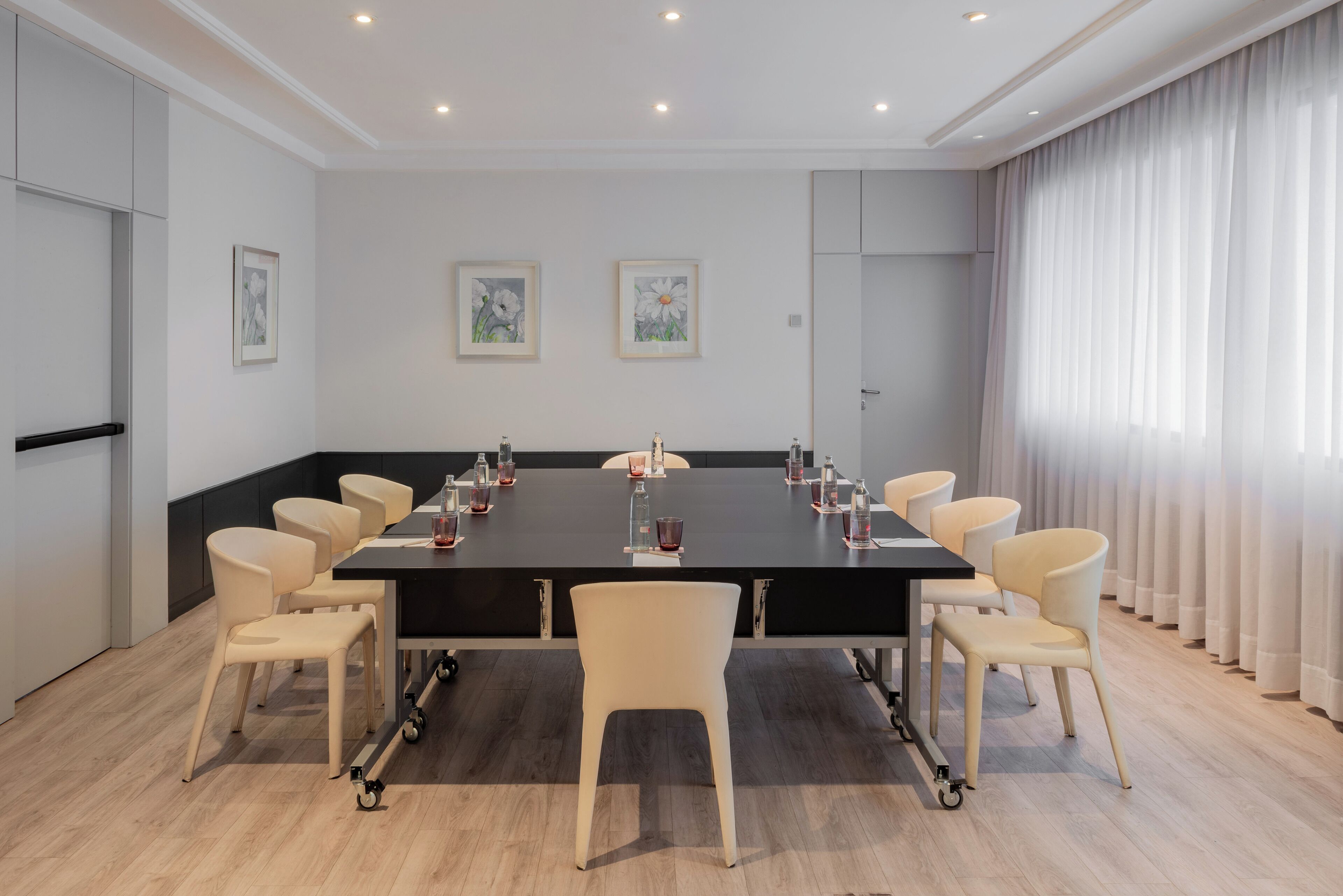 Ein Konferenzraum mit einem großen Tisch, Stühlen und Kunstwerken an den Wänden.