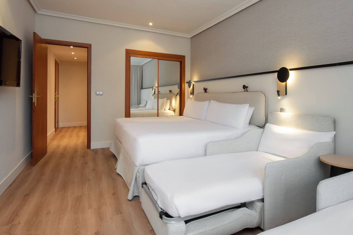 Hotellihuone, jossa on parivuode, sohva, pieni pöytä ja peili.