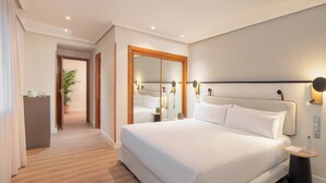 Une chambre d’hôtel moderne avec un grand lit, des tables de chevet, un miroir et une petite table d’appoint.