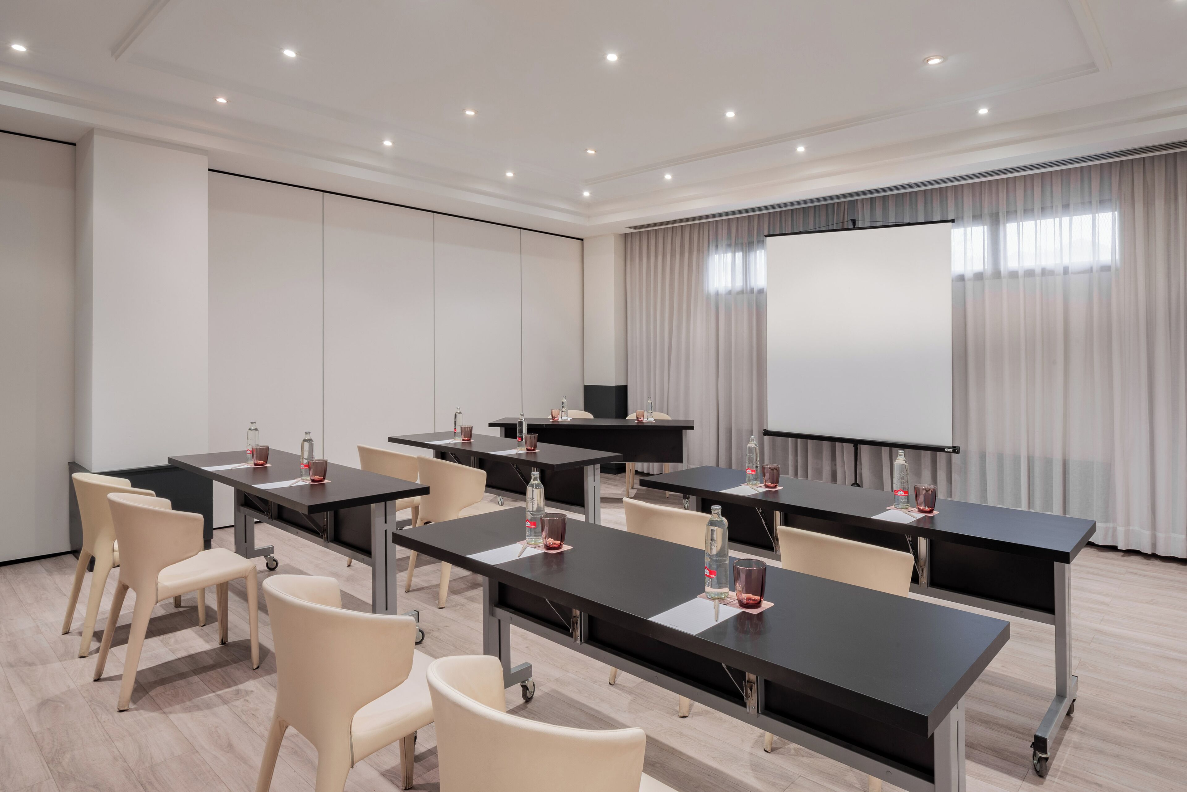 Una sala de conferencias con varias mesas, sillas y una pantalla grande.