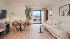 Un salon moderne comprenant un canapé, une table à manger avec des chaises, une table basse, un téléviseur et un balcon avec vue.