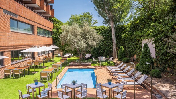 Un espace aménagé au bord de la piscine, avec des chaises longues, des tables et des parasols.