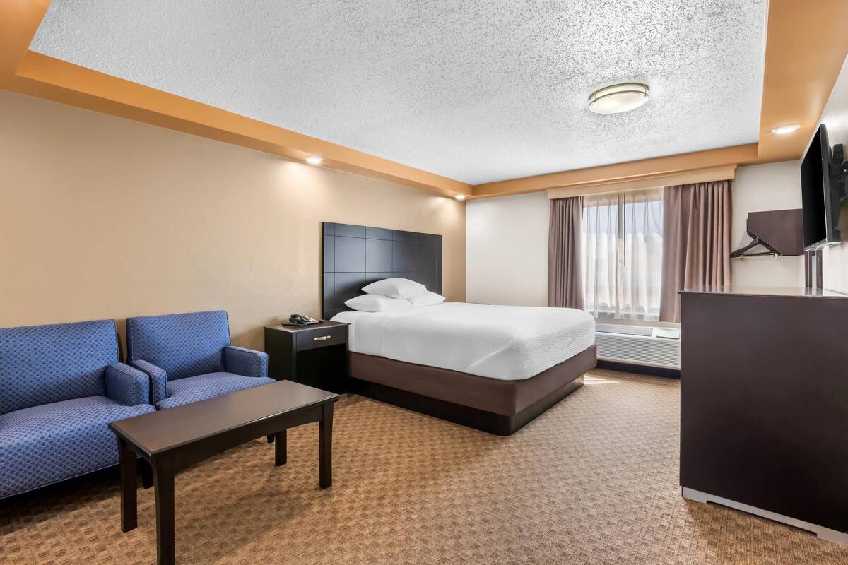Ett hotellrum med en säng, en soffa, ett skrivbord och en tv.